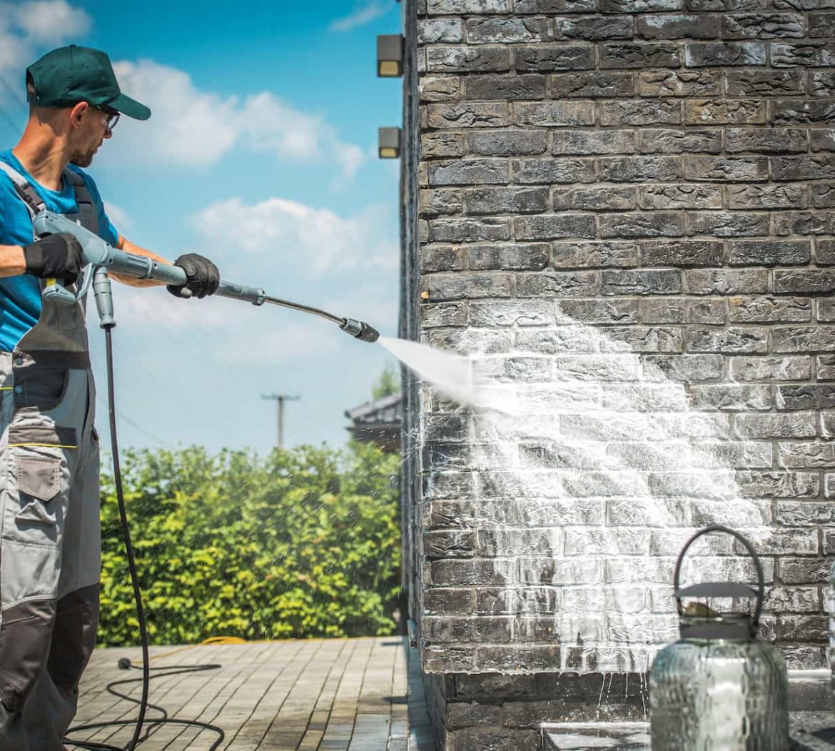 Man Using Pressure Washer on Brick Wall — Pressure Washers in Cairns, QLD